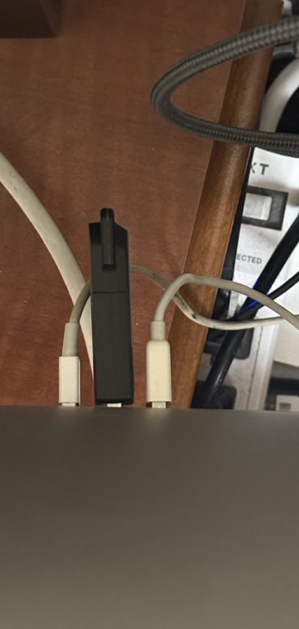 Top-down view of the USB peripherals plugged into the back of the iMac. Two neatly paired Apple cords for the keyboard and trackpad, of course... now, can you really call the boot drive a peripheral?